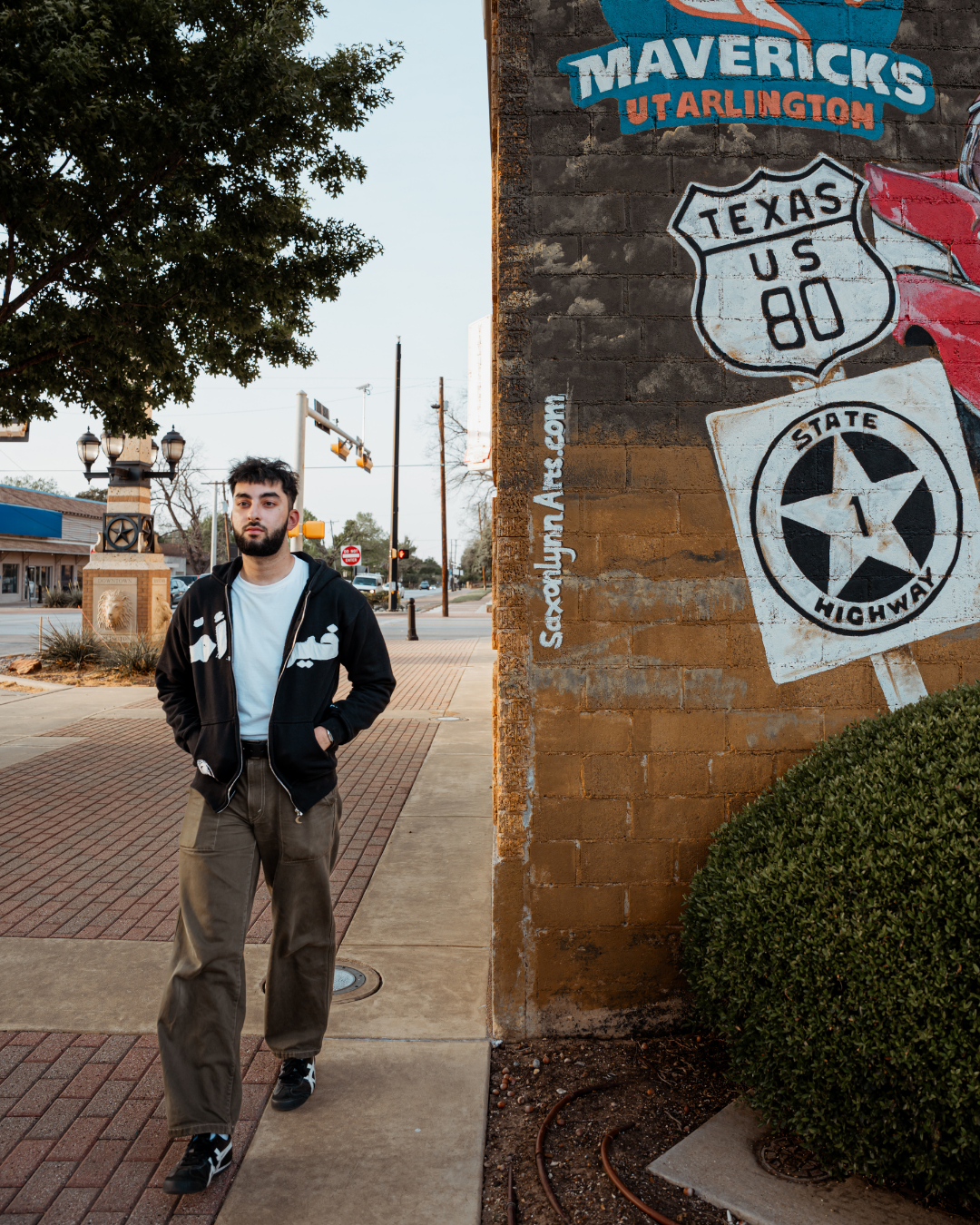 Model wearing the black Khair Ummah zip hoodie in downtown Arlington.