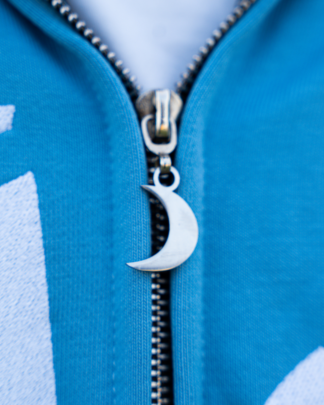 Close-up of the blue hoodie zipper with crescent moon pull.